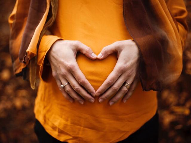 Frau mit Händen vor dem Babybauch